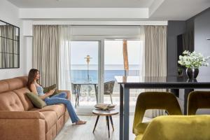 a woman sitting on a couch reading a book in a living room at Expoholidays- Apartaments Paseo Marítimo in Almería