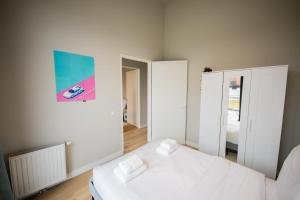 Ample 3 Bedroom Apartment في روتردام: غرفة نوم بيضاء مع سرير ومرآة