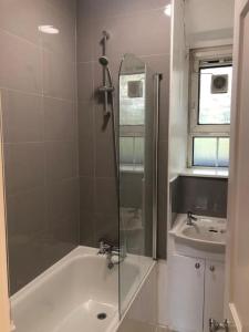a bathroom with a shower and a tub and a sink at JB Stays Greenwich Central in London