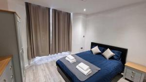 a bedroom with a blue bed with pillows on it at Skyview Strathnairn Apartment 1 in Cardiff