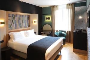 Cette chambre comprend un grand lit et une chaise. dans l'établissement HANNONG Hotel & Wine Bar, à Strasbourg