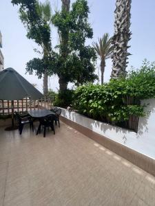 eine Terrasse mit einem Tisch, Bänken und Palmen in der Unterkunft Villa Triplex Palm Beach in Pont Blondin