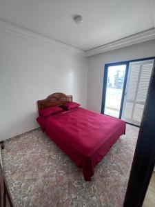 1 dormitorio con 1 cama con edredón rojo y ventana en Villa Triplex Palm Beach en Pont Blondin