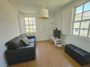 a living room with a black couch and a tv at Casa do Beco - Foz do Douro in Porto