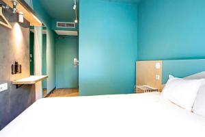 1 dormitorio con 1 cama grande y pared azul en Hotel Ibis Budget Montpellier Centre Millenaire - en Montpellier