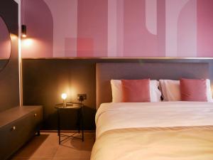 a bedroom with a bed with pink and purple walls at Eleven by Warren Collection in Sliema