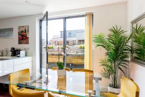 a dining room with a glass table and yellow chairs at Modern Tower Hill Penthouse in London