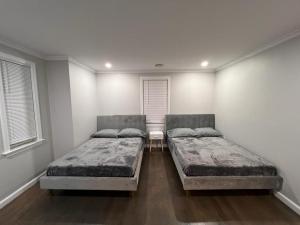two beds in a room with two windows at Single family Home ONLY long term booking of 28 days or longer in Boston