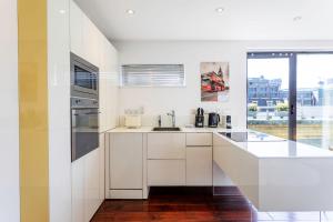 a kitchen with white cabinets and a large window at Modern Tower Hill Penthouse in London