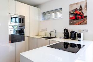 cocina con armarios blancos y encimera en Modern Tower Hill Penthouse en Londres