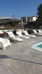 a group of lounge chairs and an umbrella next to a pool at Evita Blue in Xylokastro