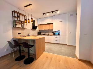 kuchnia z białymi szafkami i blatem ze stołkami w obiekcie Apartamenty Drewnowska 77 w Łodzi