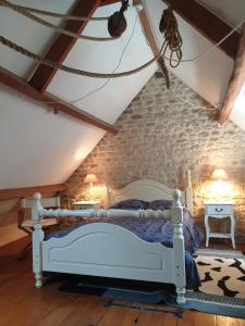 a bedroom with a white bed and a stone wall at Moulin de la Bretonnière - Omaha Beach Dday in Aignerville