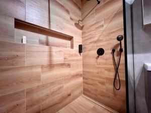 een badkamer met een douche en een houten muur bij Apartamenty Drewnowska 77 in Łódź
