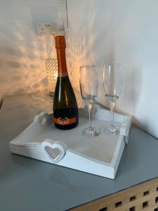 a bottle of wine and two glasses on a tray at Dolafon farm luxury glamping cabin with hot tub in St Asaph