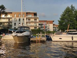 Trzy łodzie zacumowane w wodzie w pobliżu budynku w obiekcie Marina Ilavia plus garaż podziemny w Iławie