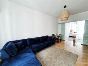a blue couch in a living room with a dog at Spacious and quiet 1BR apartment in Floreasca in Bucharest