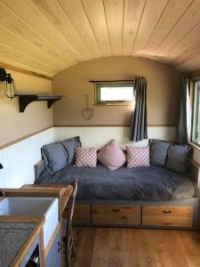 una sala de estar con sofá en una casa pequeña en The Shepherd’s Hut, en Whiteparish