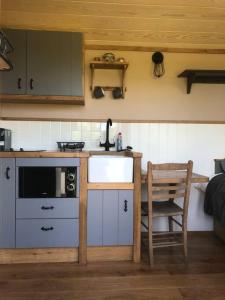 a kitchen with a counter and a sink and a chair at The Shepherd’s Hut in Whiteparish