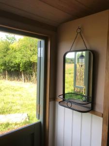 a mirror on a wall next to a window at The Shepherd’s Hut in Whiteparish