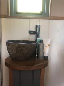 a bowl sink on a wooden table in a bathroom at The Shepherd’s Hut in Whiteparish