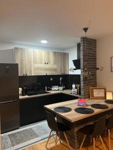 a kitchen with a wooden table with chairs and a refrigerator at Loft Luxury Apartment in Pirot