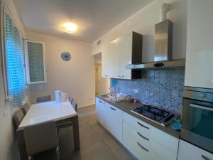 a kitchen with white cabinets and a stove top oven at Appartamento Pirandello in Lido di Camaiore