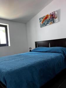 Glamping de Cerveira في فيلا نوفا دي سيرفيرا: غرفة نوم بسرير ازرق وصورة على الحائط