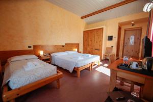 una camera d'albergo con 2 letti e una scrivania di Pràcatinat Hotel & Restaurant a Fenestrelle