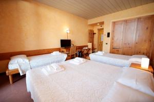 een hotelkamer met drie bedden en een televisie bij Pràcatinat Hotel & Restaurant in Fenestrelle