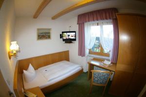 a bedroom with a bed and a desk and a television at Gästehaus Wiesenhof in Fischen +18 photos