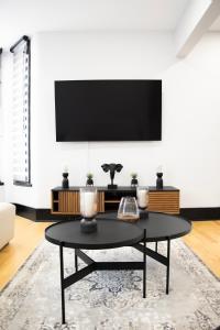 een woonkamer met een tafel en een tv aan de muur bij Eat, Explore & Enjoy Downtown Montreal at this Sleek City Escape located in Plateau Mont-Royal - Apt 4 in Montreal