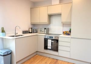 a kitchen with white cabinets and a sink at Brand new Apartment by the Marina - Sleeps 4 in Ramsgate