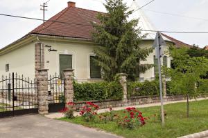 a white house with a fence and flowers at Kurucz Apartman in Sárospatak