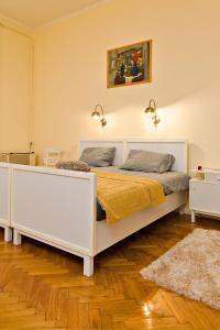 uma cama branca num quarto com piso em madeira em Kurucz Apartman em Sárospatak