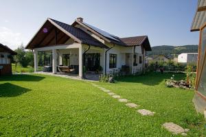 une maison avec une pelouse verte devant elle dans l'établissement Casa Mia, à Câmpulung Moldovenesc