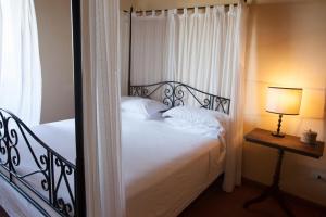 a bedroom with a bed with white sheets and a window at La Certaldina in Certaldo