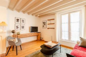 een woonkamer met een bank en een tv bij La Belle Place in Honfleur