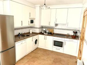 a white kitchen with white cabinets and a dishwasher at Apto La Manzanina con Parking in Villaviciosa