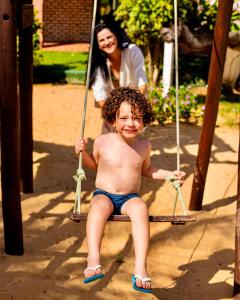 a young boy sitting on a swing with a woman at Pousada Sitio Phoenix in Prea