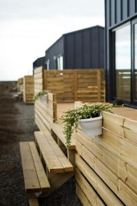 una fila de bancos de madera con macetas. en HH Gisting/Guesthouse, en Hólmur