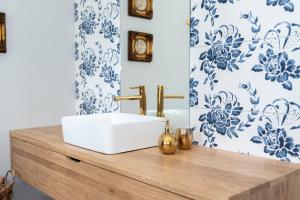 a bathroom with a white sink and blue and white wallpaper at CukroVia in Kutno