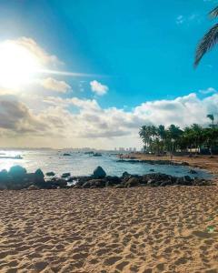 una playa de arena con el océano y palmeras en Kitnets Itapuã Residência - 1 Minuto de Caminhada Ate a Praia en Salvador
