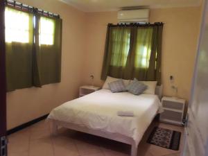 una camera da letto con un letto bianco con tende verdi di Joao's Place a Vila Praia Do Bilene