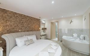 1 Schlafzimmer mit einem weißen Bett und einer Badewanne in der Unterkunft LUXURY VILLAS ELENI STEFI in Limenas