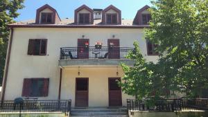 ein weißes Haus mit einem Balkon mit Blumen darauf in der Unterkunft Apartman Popovic Cetinje in Cetinje