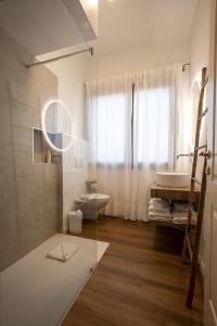 bagno con servizi igienici, lavandino e specchio di Il Borgo Boutique Rooms by KasaVacanze a Porto San Paolo