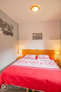 - une chambre avec un grand lit rouge et deux lampes dans l'établissement Au refuge d'Hirka, à Termignon
