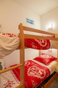 a bedroom with two bunk beds with red sheets at Au refuge d'Hirka in Termignon