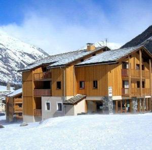 a large wooden building in the snow with mountains at Au refuge d'Hirka in Termignon